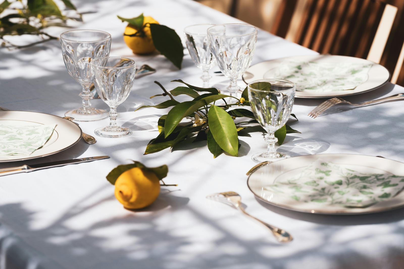 A table laid with crystal glasses and lemons in dappled sunlight