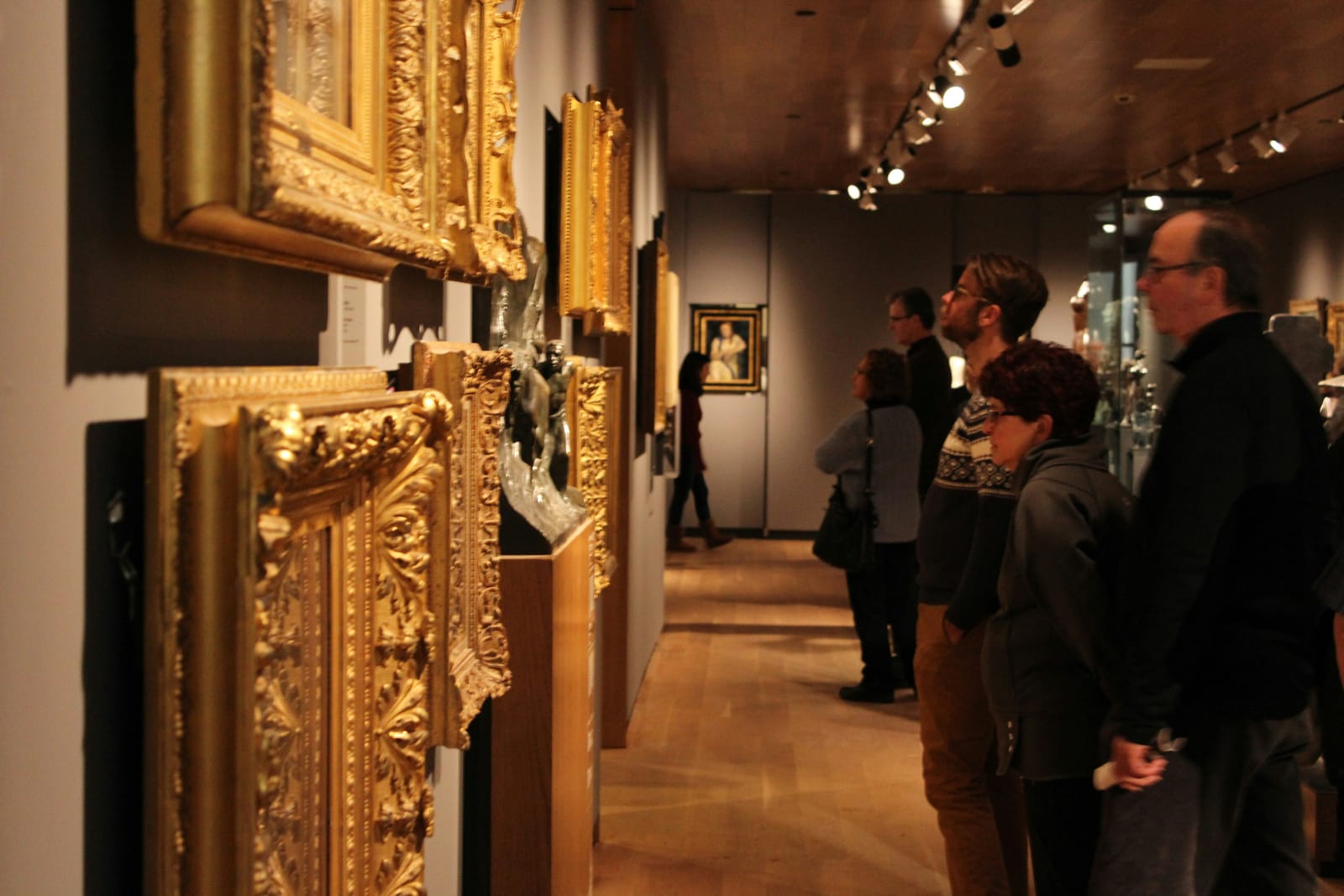 Visitors viewing gilded picture frames in a museum gallery