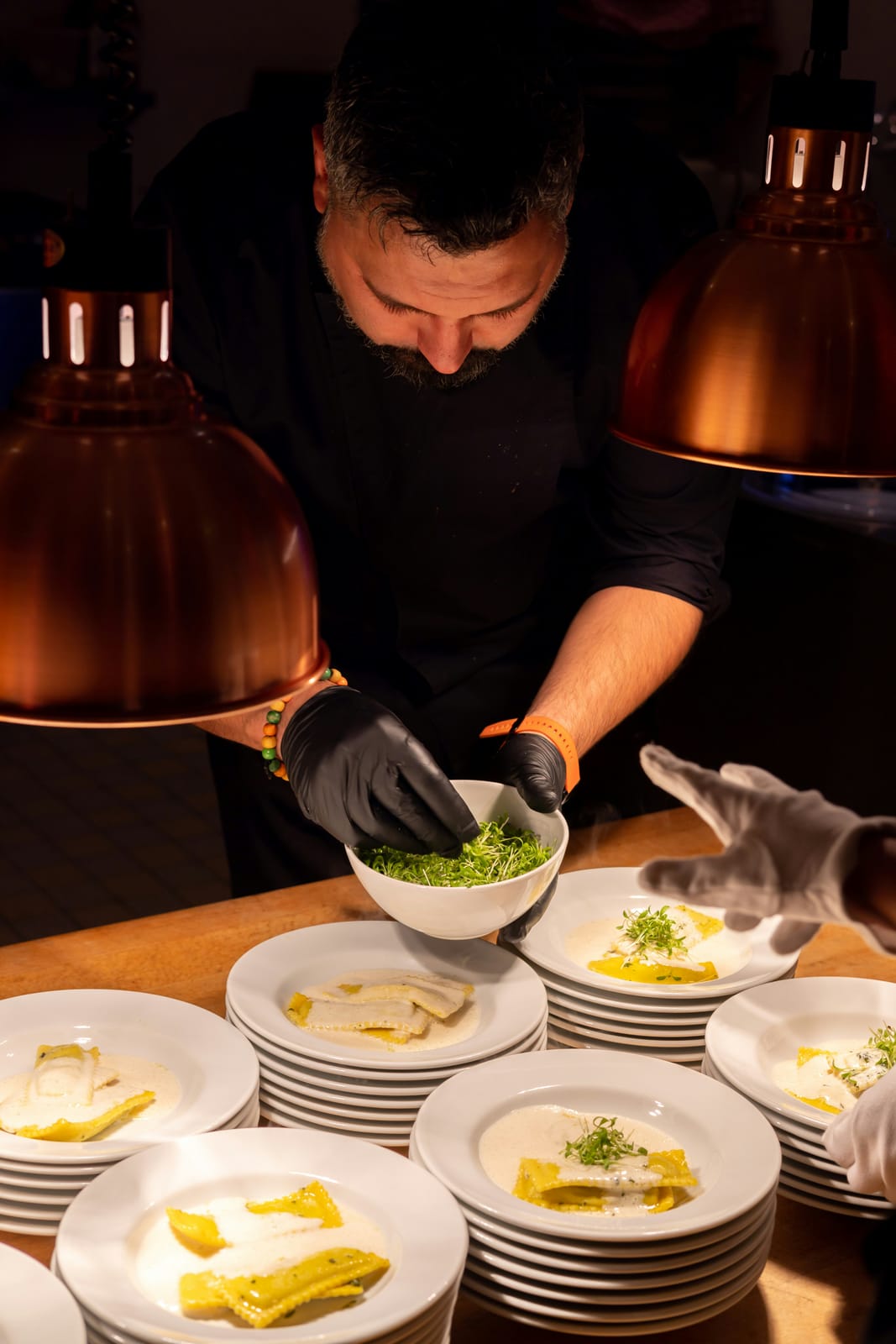 A chef plating several dishes under warm light
