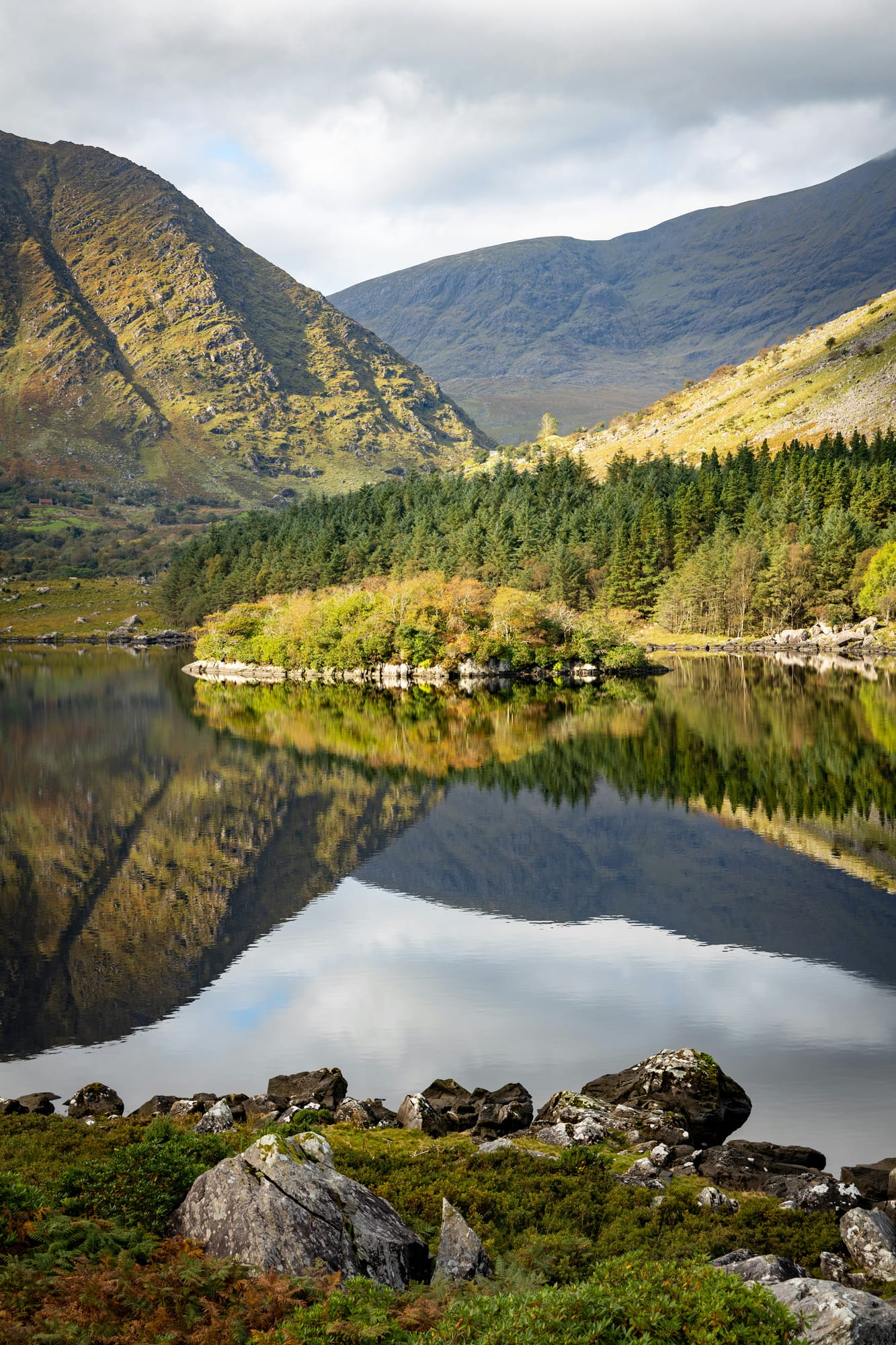 A still lake in the Killarney landscape framed by mountains and autumn colour