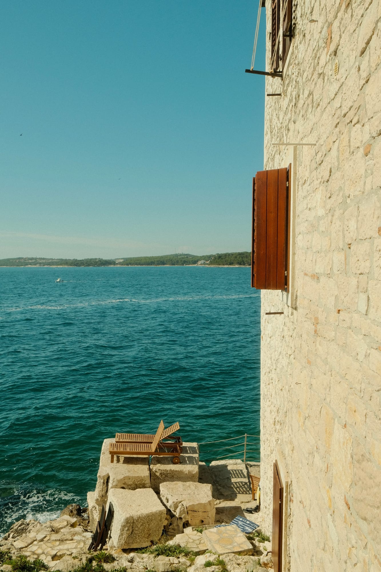 A stone house with wooden shutters above the turquoise Adriatic on the Istrian coast