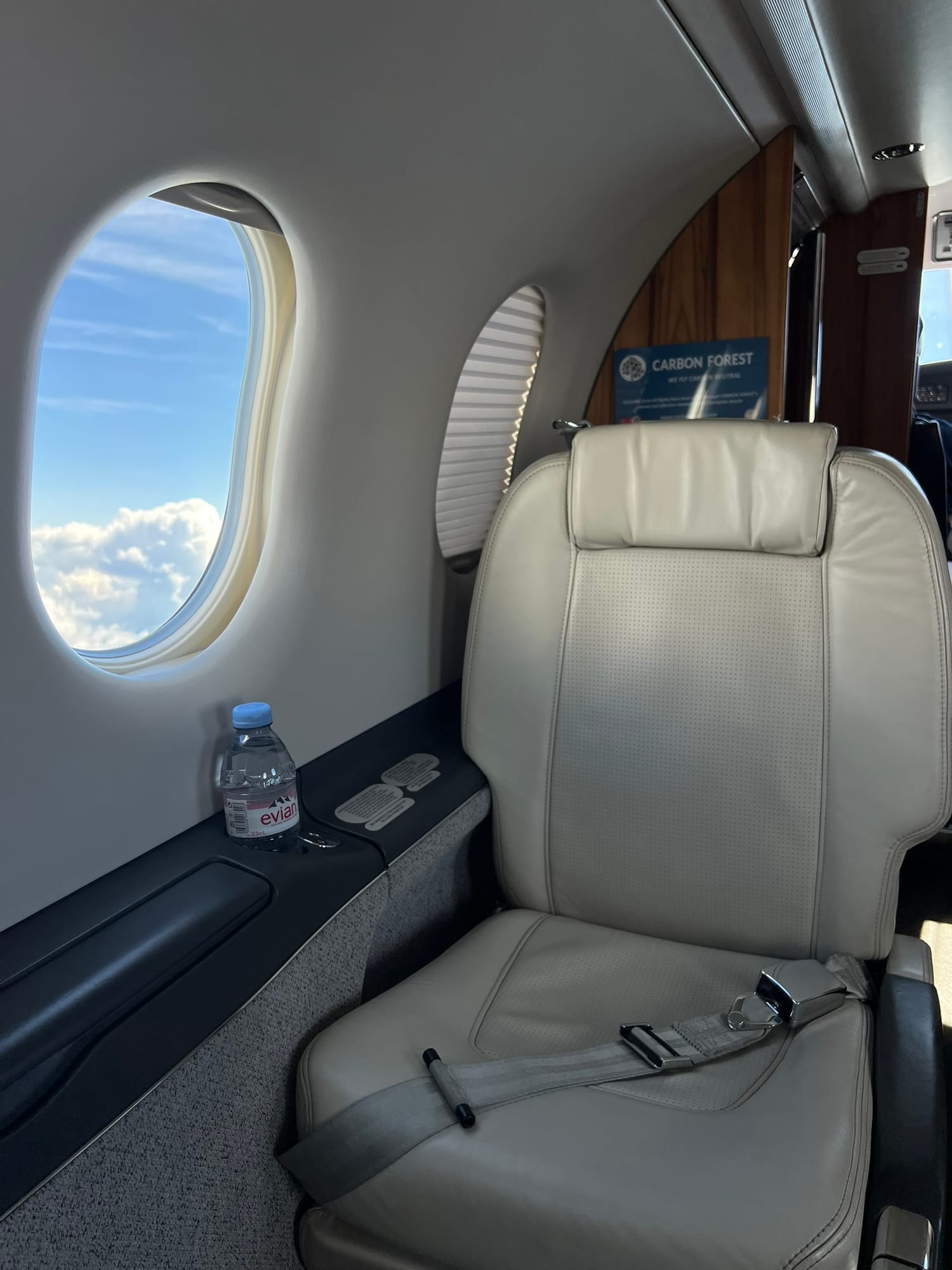 The cabin of a private jet with a leather seat and a view of the sky