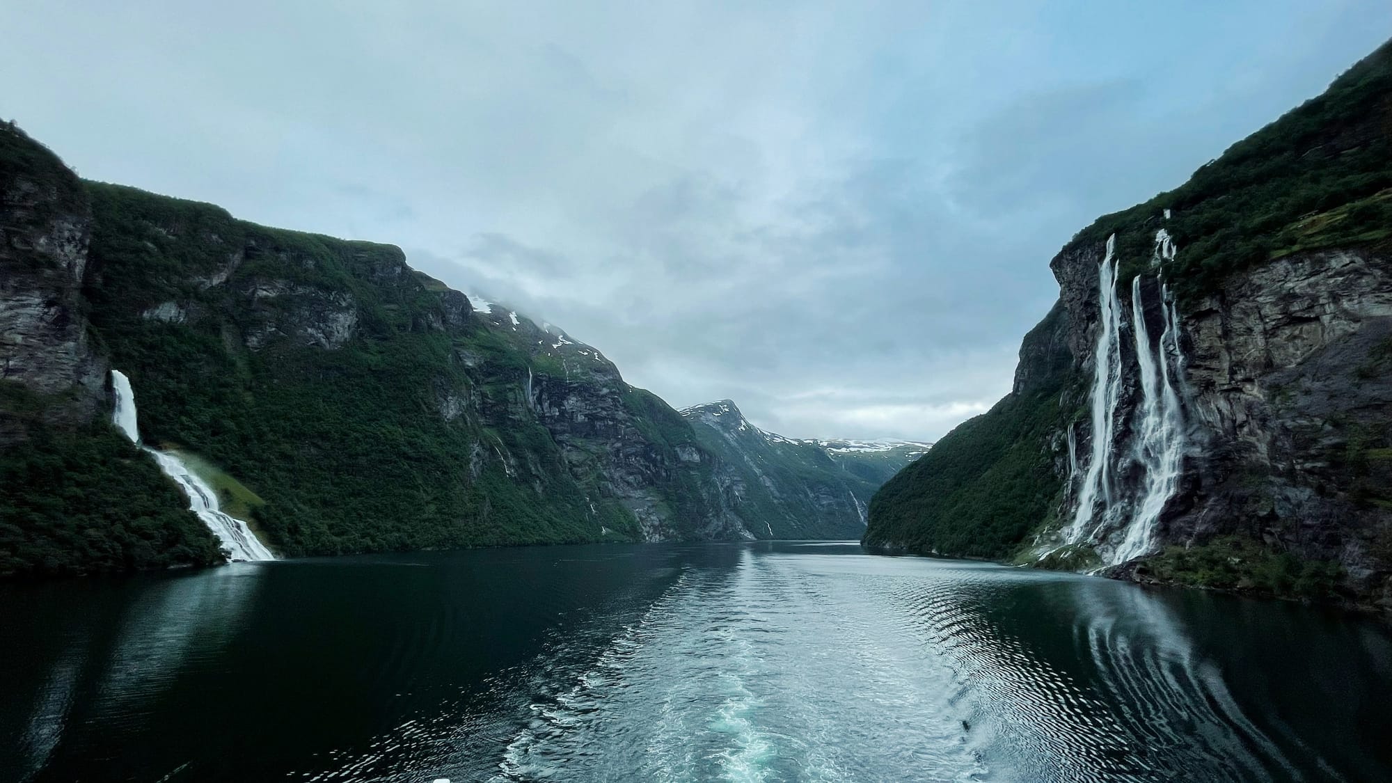 Waterfalls tumbling down steep cliffs into a Norwegian fjord
